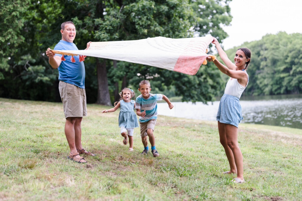 Kids are playing under the blanket during a lifestyle outdoor family photography session by Ivy Lulu Photography in Metrowest Massachusetts