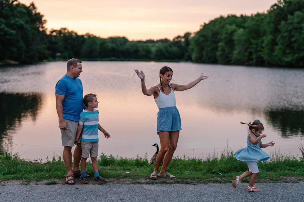 The little girl is dancing during a lifestyle outdoor family photography session by Ivy Lulu Photography in Metrowest Massachusetts