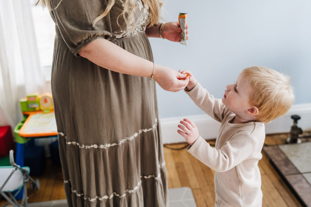 The little boy is getting snack from mom during a newborn photography session