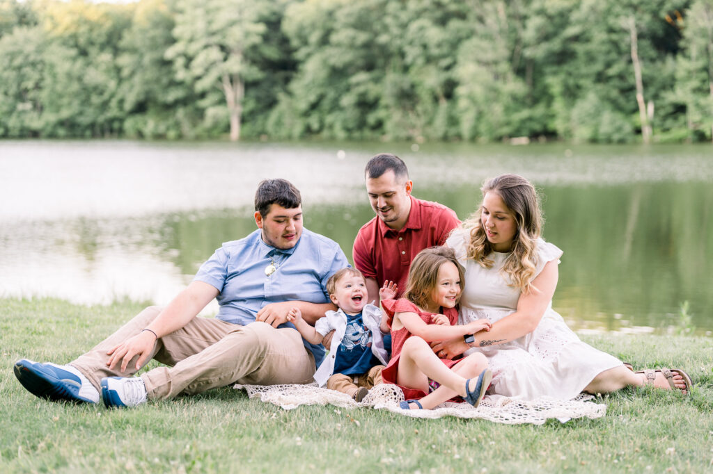 Family members are sitting down on the grass during a lifestyle family photography in Massachusetts