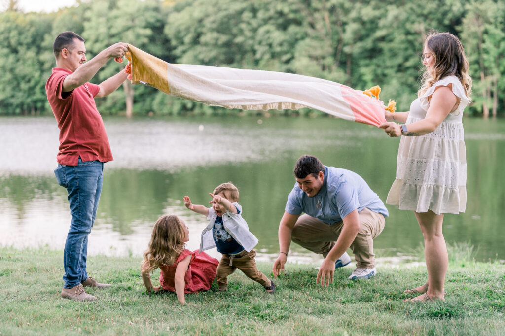 Kids are playing under a blanket during a lifestyle family photography session in Massachusetts by Ivy Lulu Photography