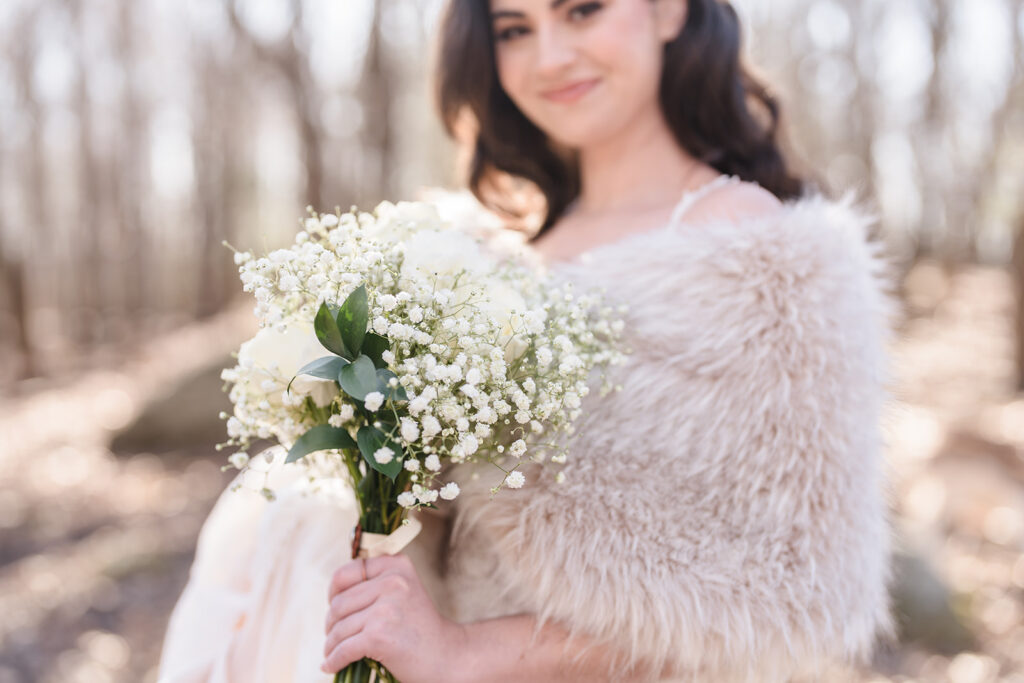 The bride is smiling and holding her white bouquet during her elopement wedding at Southwick's Zoo.